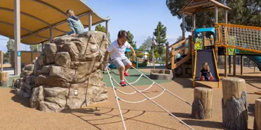 Young Child Playing On Climbing Net And Rocks - Image Credit Landscape Structures